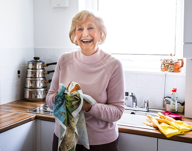 Photo of an older female laughing as she washes up